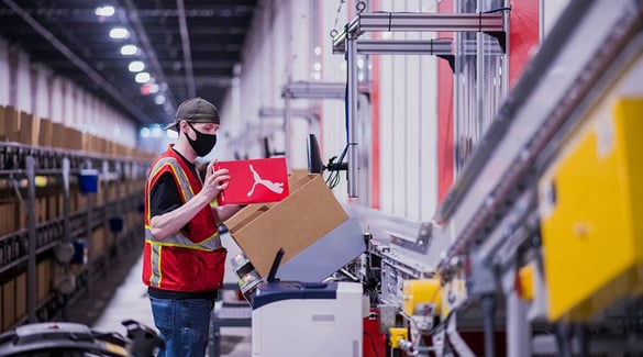 A worker puts a stock in a box for shipment at PUMA