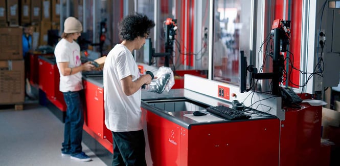 An example of automated equipment and robotics assisting human operators. In this case, robotics has&nbsp;delivered the products to the human operators at workstations. The system's software informs the operator what items to pick and how many items to pick.