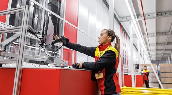 A worker touches computer screen while fulfilling orders at DHL