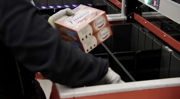 A worker pulls an item from an AutoStore Bin