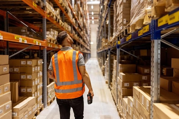 Warehouse worker walking down an aisle between shelves