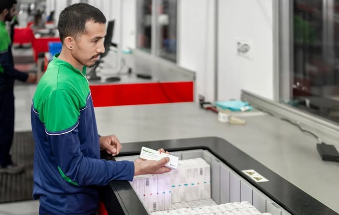 A worker pulling inventory from AutoStore Bin at workstation