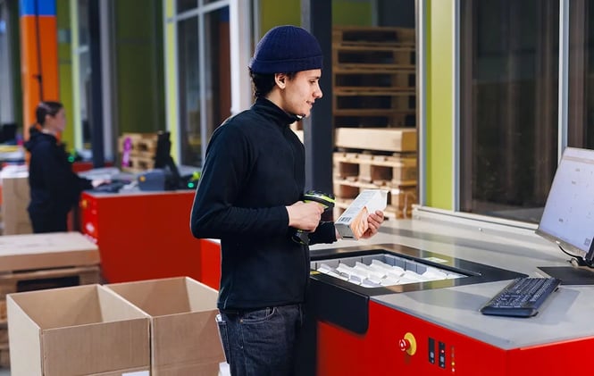 A worker scans inventory at an AutoStore workstation