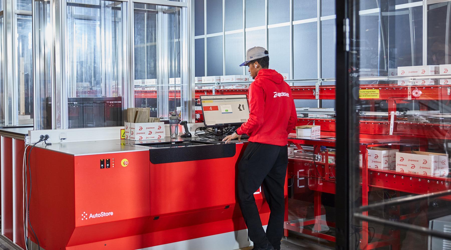Warehouse workers picking items from inventory Bins delivered to a workstation by warehouse robots.