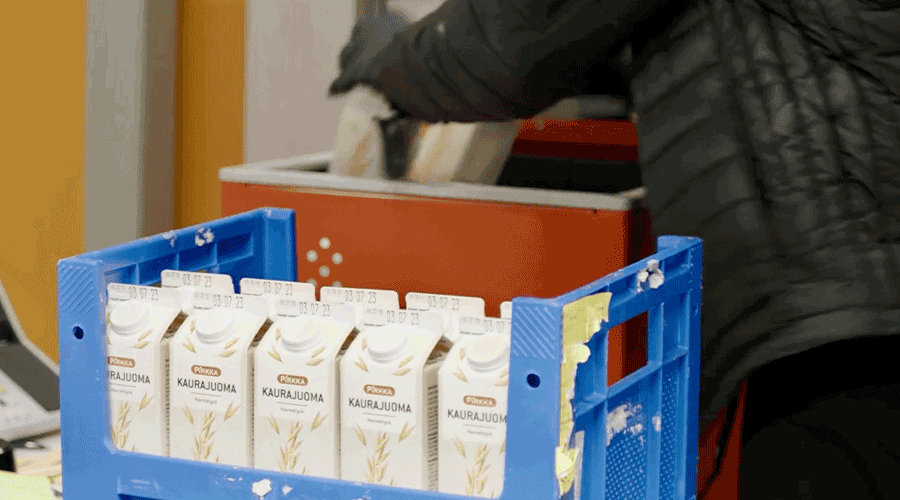 Woman loading inventory into AutoStore ConveyorPort. Image.