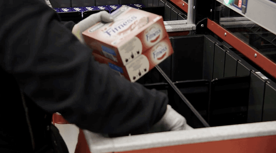 Person loading inventory in to AutoStore ConveyorPort at Kesko in Finland. Image.