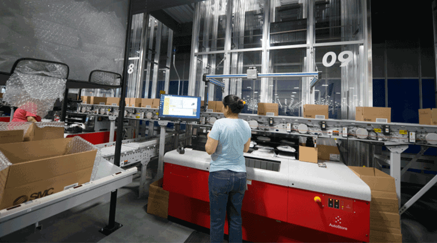 A woman processing orders at an AutoStore Port. Image.