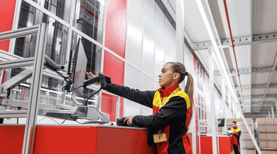 Warehouse workers at DHL picking items from AutoStore cube storage Grid. Image.